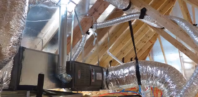 Technician installing new air ducts in an attic